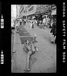 A man on the ground of a busy sidewalk