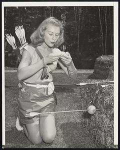 Free-Style Champ -- 15-year-old Ann Marston of Wyandotte, Mich., who won the women’s free-style archery event at Newbury, N.H., although her age entitled her to compete with the juniors. She is eating an orange she used as a target in a practice session.