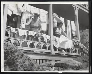 Hang Out Laundry in Flood Area- Two unidentified woman hang out laundry on porch of flood stricken home in Southbridge yesterday as rehabilitation work proceeded. Note debris in foreground. The area was hit with up to 12 inches of rain and severe flood conditions.