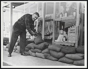 Keeping the Sauce Dry - John Eagan places sandbags in front of his package goods stone in downtown Taunton.