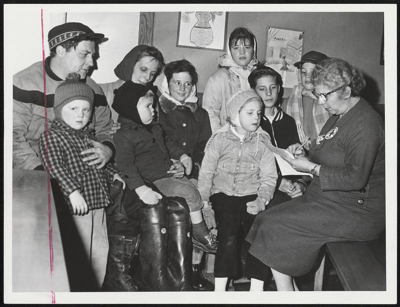 Driven From Home by flood tides during the blizzard, the family of Mr. and Mrs. Robert Redman of Hull list their needs with Miss Anita Calabro of Hull Red Cross chapter disaster services committee. The children, from left, are John, Joseph, Coleen, Kathleen, Cheryl, James and Daniel.