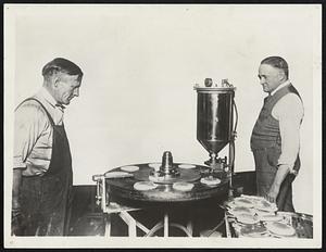 "Stack O' Wheats" Up-To-Date! -- Automatic Pancake Machine Turns Out 380 Flapjacks an Hour -- Ideal for Army Cooks, Hotels and Restaurants. The inventors and manufacturers, Coleman and Lamprecht, with their clever new pancake-making machine. The batter is in the can at right. Every 10 seconds, enough batter for a cake is squirted on to the round revolving pan, which is heated by electricity. When the cake has gone half way around, the automatic turner, at left, flips it over, and by the time it has gone all the way around it is cooked and another turner flips the finished product off the turn-table-stove. The machine turns 'em out at the rate of 380 an hour, and it is called ideal for army and navy purposes and for large hotels and restaurants.