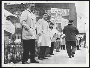 Supporters for rival unions gather at Lynn General Electric plant today as balloting for representation started among workers. Campaigners for International Union of Electric Workers, AFL-CIO, display placards. Supporters for rival independent United Electric Workers pass out leaflets.