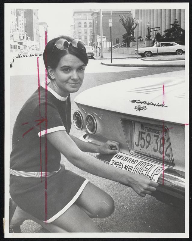 Mrs. Nancy Hughes, a striking kindergarten teacher, attaches sticker to car bumper.