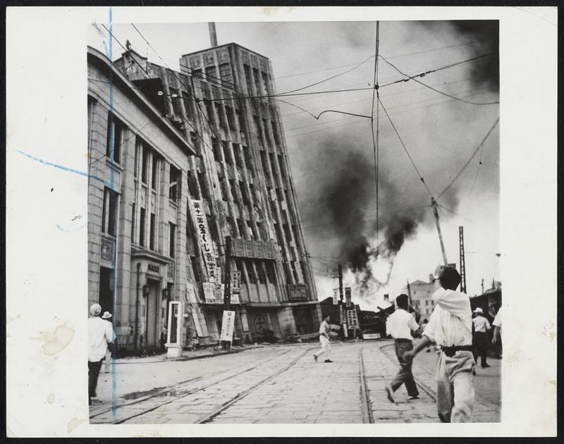 Daiwa Department Store Totters. The steel and concrete Daiwa department store in Fukui, Japan, Totters on its foundation after the earthquake which shook the area June 28. Japanese scurry in search of shelter as fires rage in background.