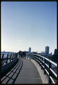 People walking on footbridge, Cambridge in background