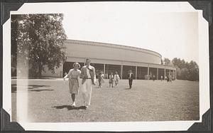 An unidentified man and woman walking on the lawn in front of the Koussevitzky Music Shed