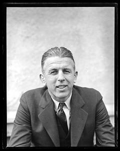 Unidentified man standing by a car, cigarette in hand