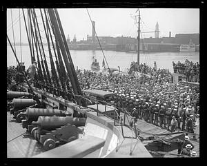 A crowd of people on the dock by a ship, probably the USS Constitution