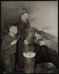 Whitney Farm - Marlboro, VT when it reaches 219 degrees in temperature, the boiling syrup is considered done - Mrs Whitney is drawing some out of the evaporating tank while Harold Whitney, Jr. is trying it out