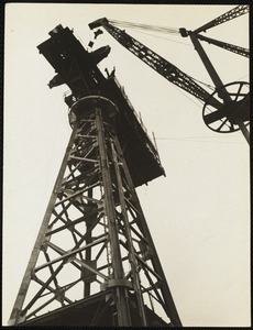 Materials are raised by the large crane alongside of tower.