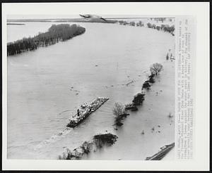 A Barge of Rock for the Levees--A towboat heads up the flooded Missouri River from Omaha with a barge load of rock to strengthen a levee against the worst crest in history. The channel of the River normally runs between the two lines of trees.