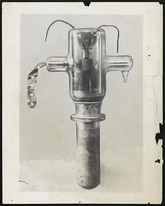 New "Cold" Radio Tube.- Animals have been killed, the temperature of the human body reached several degrees and 6000 has been cooked by the cold heat generated in a new high power, short-wave tube developed in the laboratories of the General Electric Company in Schenectady, N.Y.-The tube which causes these strange phenomena is a harmless looking vacuum tube, 5 inches in diameter and about two feet long, set in a wooden cage surrounded by a network of wires, condensers and electric meters. Photo shows the "cold" radio tube.-