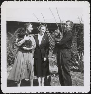 Olga Koussevitzky standing with an unidentified man and woman who are both holding dogs