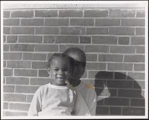 Two girls sitting in front of a brick wall