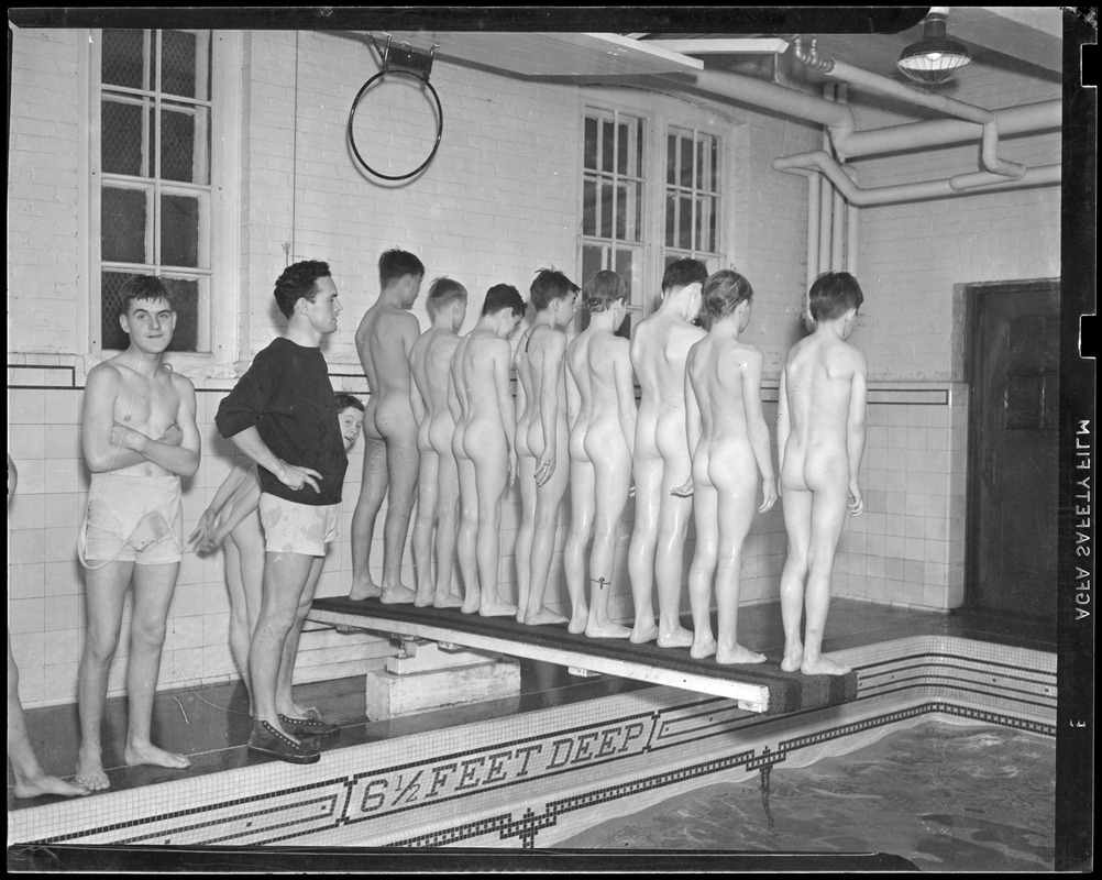 Row of naked boys stand on diving board at indoor pool