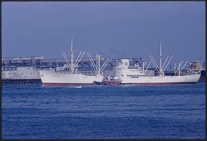 Large white ship and tugboat in Boston Harbor