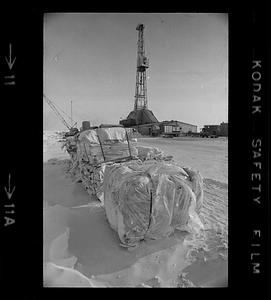 Supplies for BP Alaska oil operation, derrick in background