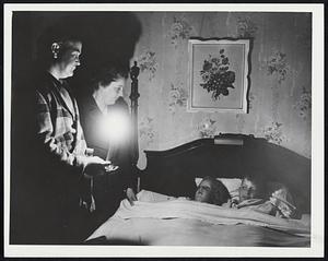 Back to Candlelight went most Greater Boston families last night after the hurricane cut off electricity. Here Mr. and Mrs. Harry Palmer put their children, Barbara, 6, and Harry, 10, to bed by candlelight at 77 Templeton Pkwy., Watertown.