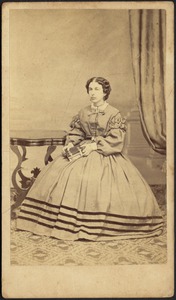 Woman in dress with striped hem; seated holding book