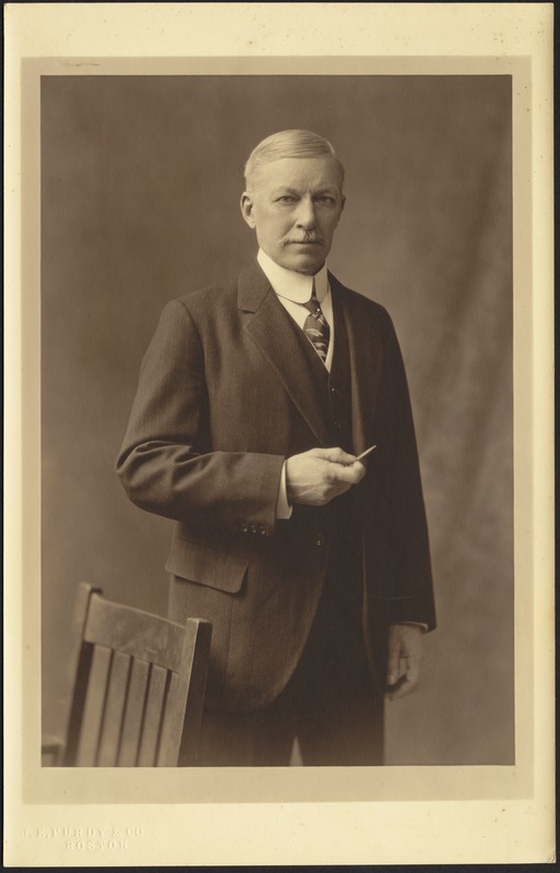 Portrait of John Gardner Coolidge standing near chair