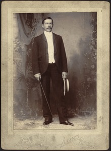 Studio portrait of John Gardner Coolidge holding straw hat and cane