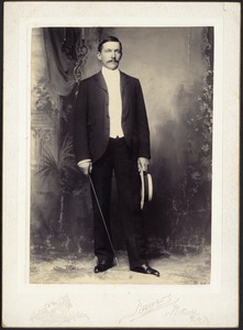 Studio portrait of John Gardner Coolidge holding straw hat and cane