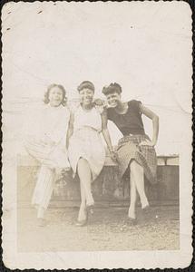 Three women pose sitting