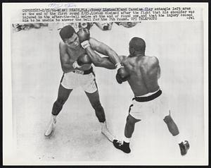 Sonny Liston (R) and Cassius Clay entangle left arms at the end of the first round 2/25. Liston claimed after the fight that his shoulder was injured in the after-the-bell melee at the end of round one, and that the injury caused him to be unable to answer the bell for the 7th round.