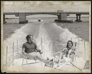 With other friends at the helm and in the gallery, this couple relaxes on the aft deck of a rental houseboat - in St. Petersburg, Florida. The Bayway Bridge – spanning Boca Ciego and Tampa Bay, is in the background.