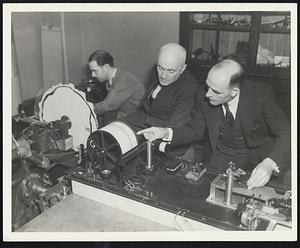 The laboratory of seismology at MIT with laboratory technicians watching the recording of earth disturbances on the seismograph machine.