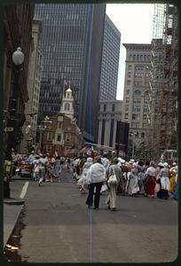 A group of people, some in colonial costume, walking toward Old State House, Boston