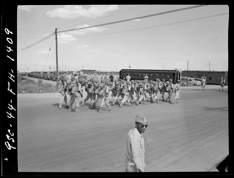 Group of soldiers with packs and rifles walking