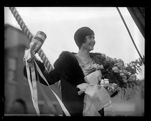 Unidentified woman holding a bouquet of flowers and a wrapped bottle