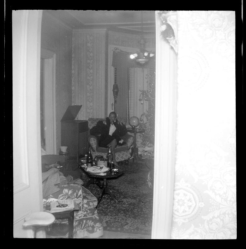 A woman is seated in an armchair next to a Christmas tree