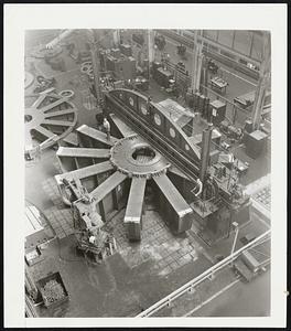 Huge Bracket For McNary Dam. Machining Giant Bracket -- A 41-foot bearing bracket of 70,000 kilowatt hydraulic turbine-driven generator for McNary Dam is shown on a 42-foot boring mill in the General Electric Co. plant at Schenectady. Workmen on top of the bracket are dwarfed by its size.