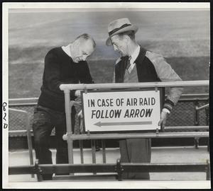 Dem Bums Ready for Dem Bombs at Ebbets Field in Brooklyn, where workmen are shown placing signs to direct the Flatbush faithful "just in case." These grim reminders of baseball's war year will be seen by Brooklyn fans this week-end in the exhibition series with the Yankees.