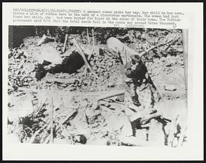 A peasant woman picks here way, her child in her arms, across a pile of rubble here in the wake of a disastrous earthquake. The woman had just found her child, who had been buried for hours in the ruins of their home. The Turkish government said 8/21 that the total death toll in the quake may exceed three thousand.