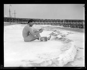 A man sits on snow in the nude