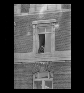 Man sitting in window, possibly an anti-war protester