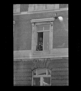 Man sitting in window, possibly an anti-war protester