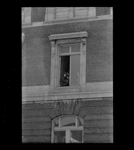 Man sitting in window, possibly an anti-war protester