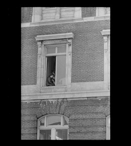 Man sitting in window, possibly an anti-war protester