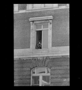 Man sitting in window, possibly an anti-war protester