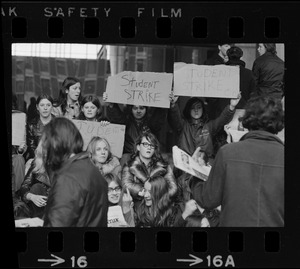 Boston high school students sit on steps at City Hall to display their strike signs during demonstration on City Hall Plaza