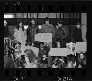 Boston high school students sit on steps at City Hall to display their strike signs during demonstration on City Hall Plaza