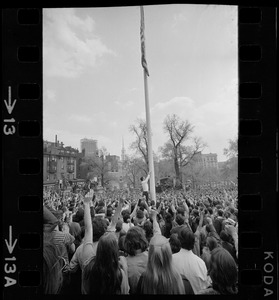 Man lowering flag to half-staff during anti-war protest at the Massachusetts State House