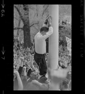 Man lowering flag to half-staff during anti-war protest at the Massachusetts State House