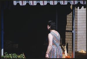 Woman walking into store selling vegetables, Boston