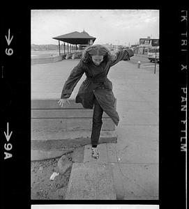 Person wearing trench coat jumping from wall